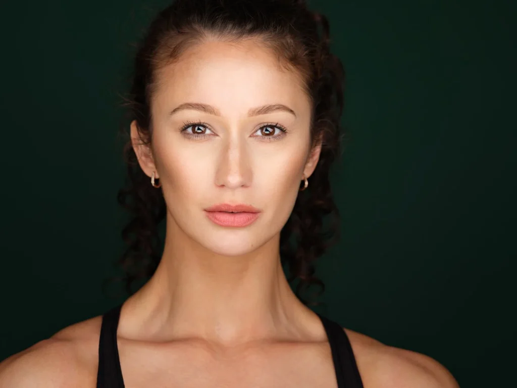 Theatrical actor headshot of a woman against a dark green background, Toronto casting headshot
