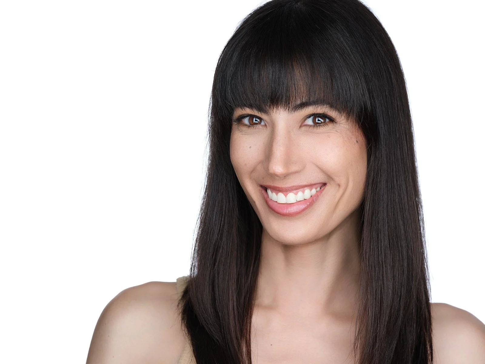 Close-up of a woman with long dark hair and bangs smiling against a white background.