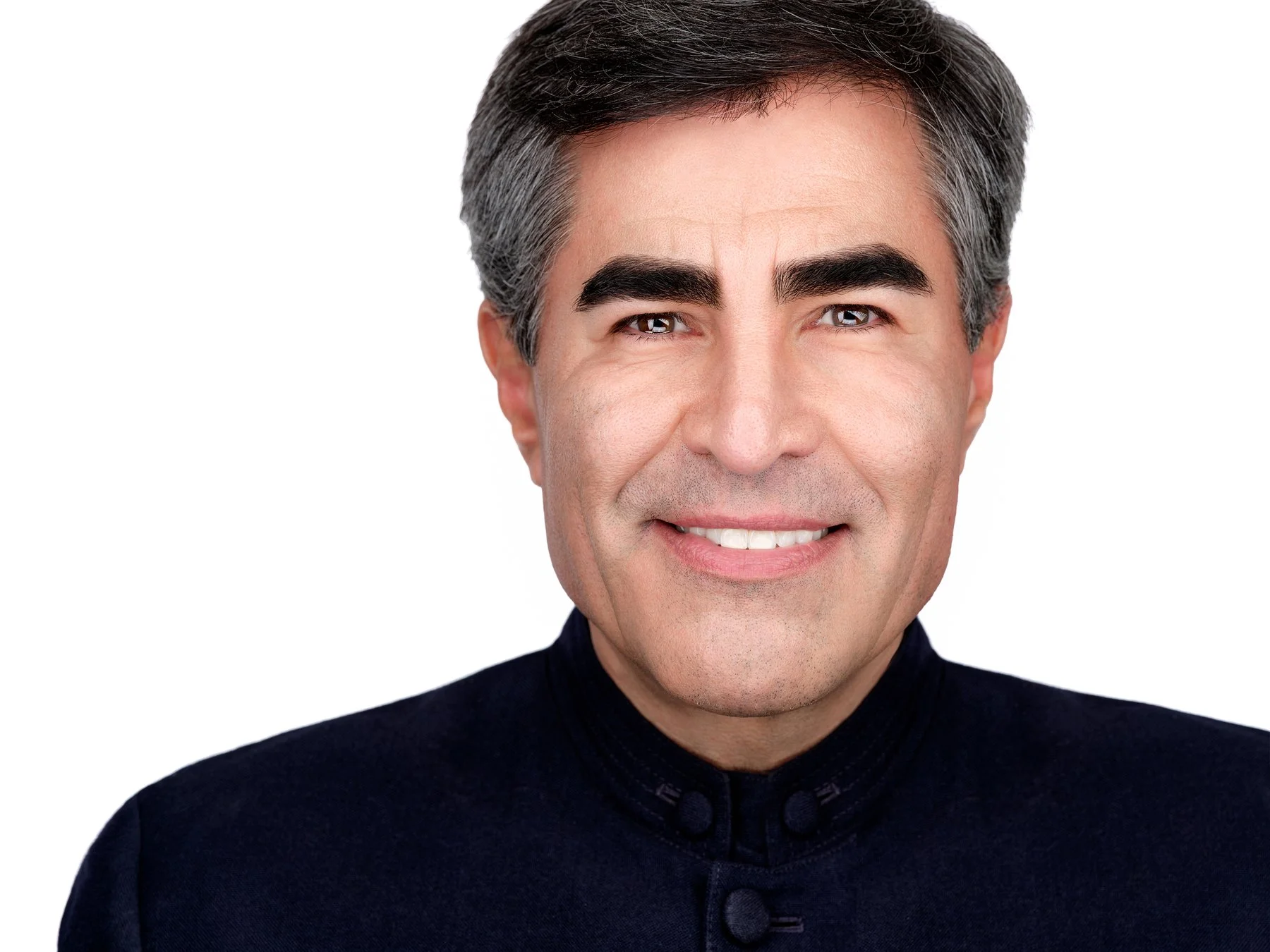 Close-up of a smiling middle-aged man with dark hair streaked with gray, wearing a black traditional Chinese-style jacket, against a plain white background.