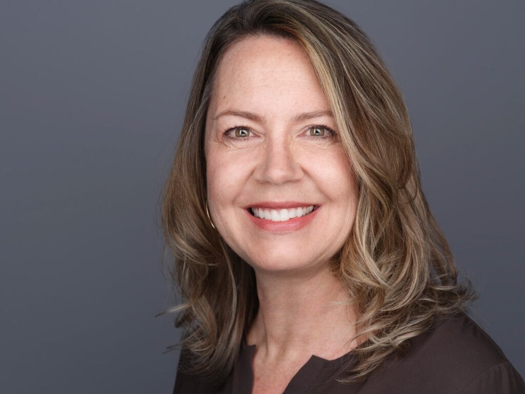 LinkedIn headshot of a woman smiling against a soft grey background, Toronto studio