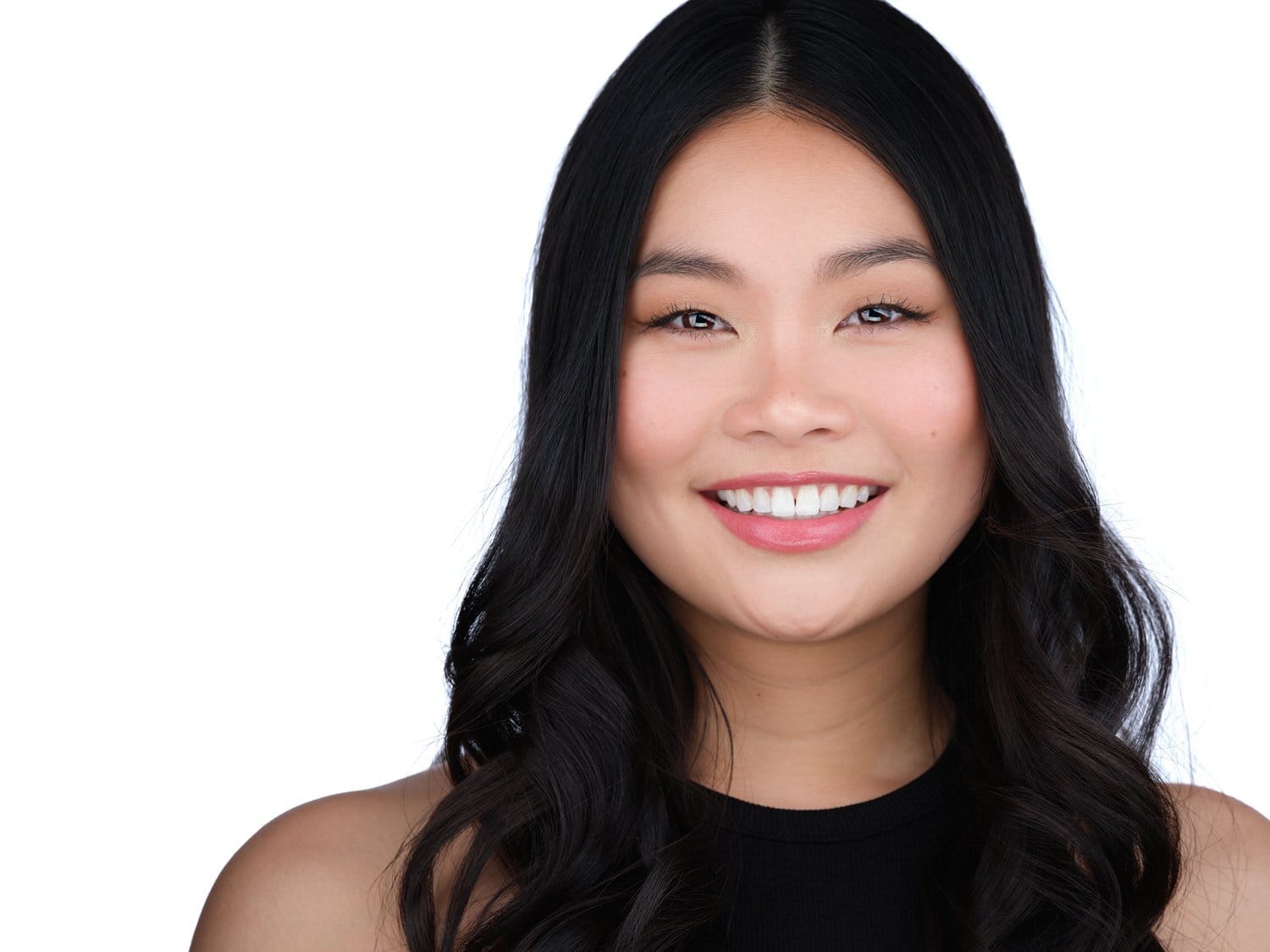 Portrait of a smiling young woman with long black hair against a white background.