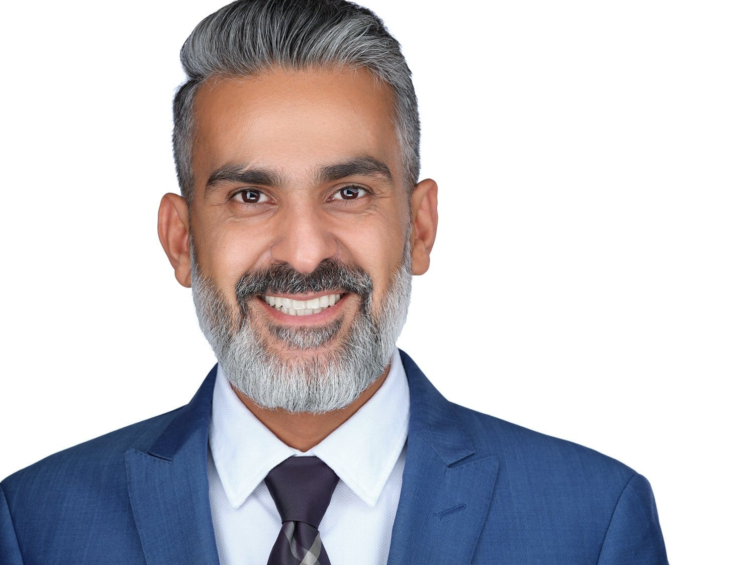 A smiling middle-aged man with gray hair, a gray beard, wearing a blue suit, white shirt, and patterned tie, against a white background.