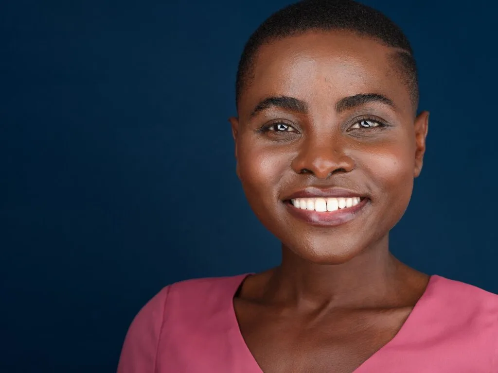 Corporate headshot of a woman in a pink top smiling against a navy background, Toronto studio